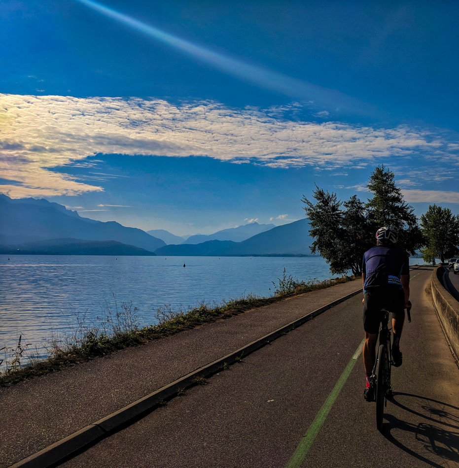 A cyclist riding next to Lake Annecy on a cycle path