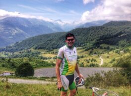 cyclist standing at the summit of col du couraduque. Large Pyrenees mountains in the background
