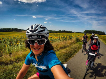 A group of cyclists riding past sunflowers in France
