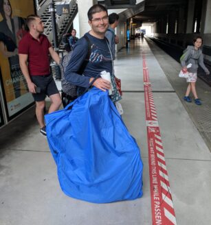 Man waiting on train platform with bicycle packed in a Rinko bag