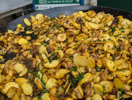 A dish of roasted potato slices with bacon and mushrooms at the food markets in Sarlat la Caneda France